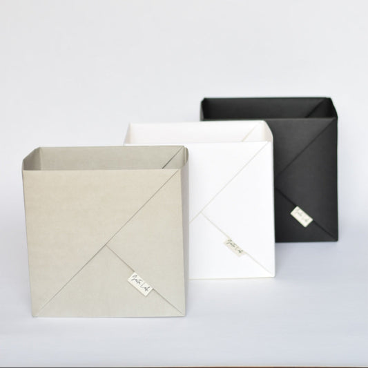 Three washable paper origami baskets  in black charcoal, warm white, and stone on a light white background - Gaita Lab