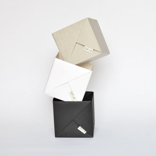 Three washable paper origami baskets jewelry boxes in black, white, and stone on a light white background - Gaita Lab