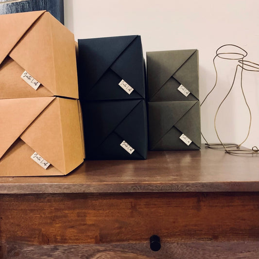 Three washable paper origami baskets small,, two brown, two deep olive  and two black, on a wooden surface with a neutral background - Gaita Lab
